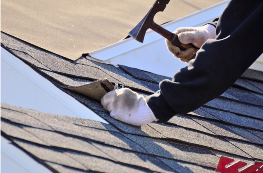 A roofer repairing shingles on a residential roof