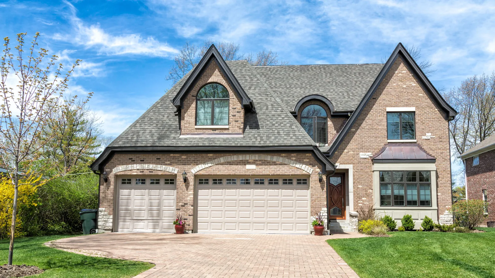 Gray architectural shingle roof on a brick two-story with steep gables