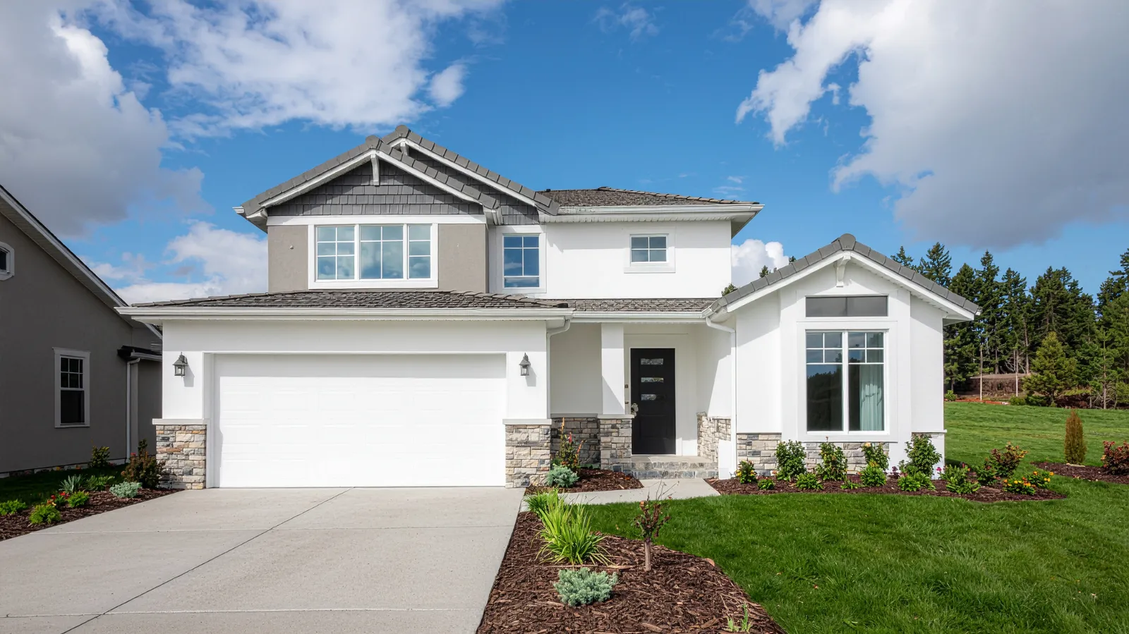 Stone accent columns on a two-story home under a gray shingle roof