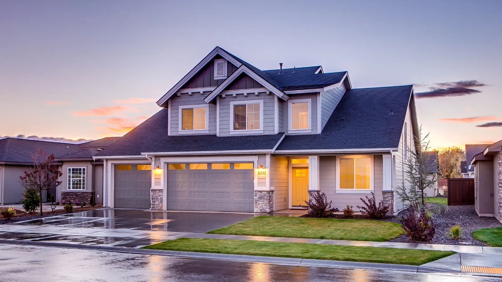 Dark shingle roof on a gray two-story home at dusk