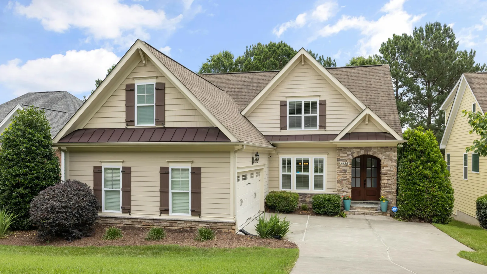 Stone arched entryway on a tan home under a brown shingle roof